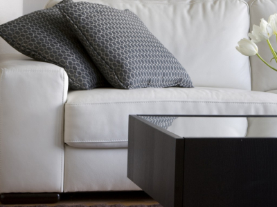 Image of a clean, white couch and two pillows behind a coffee table.